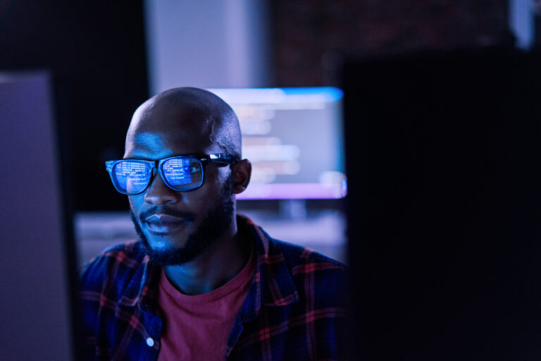 Cyber Security, Black Man And Code Reflection In Eyewear, Hacking And Software Update In Office. African American Male Employee, Programmer Or It Specialist With Glasses, Focus And Cloud Computing