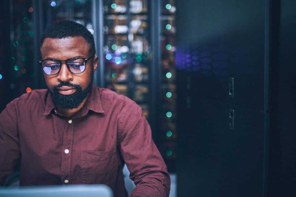 Shot Of An Male It Technician In A Server Room And Using A Laptop