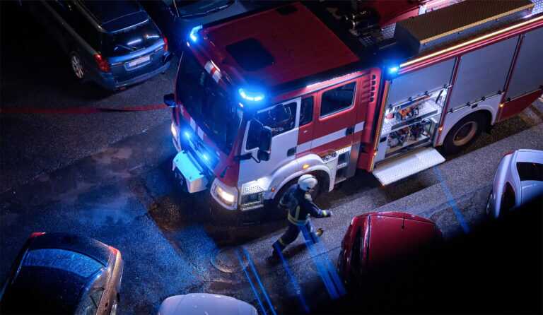 Fire Truck At An Urban Emergency Scene At Night. Firefighter On